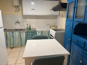 una cocina con armarios azules y una mesa y sillas blancas. en Yiayia Katina’s House en Korinthos