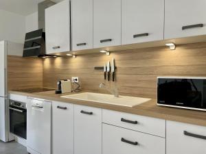 a kitchen with white cabinets and a sink and a microwave at Alba in Laxou