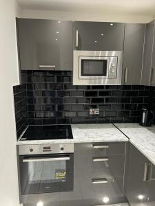 a kitchen with a stove and a microwave at T Lodge in Abbey Wood +22 photos