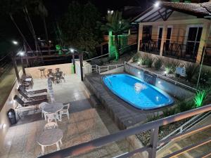 an outdoor swimming pool at night with a table and chairs at Pousada Vila do Navegante in Bombinhas
