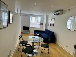 a living room with a blue couch and a glass table at New 2A Soho Studios by Indigo Flats Sleeps 4 in London
