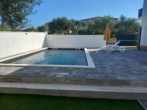 a swimming pool in a backyard with a fence and an umbrella at Apartment with a pool mountainview near the sea! in Posedarje