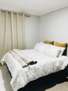 a bedroom with a bed with white sheets and pillows at Stunning Modern Home in Maseru in Maseru