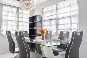 a dining room with a glass table and chairs at The Calle Retreat by the Airport & Beach in Carolina