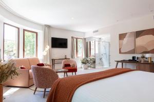 a bedroom with a bed and chairs and a television at La Bastide Bourrelly - Mathias Dandine in Cabriès