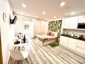 a room with a bed and a table and a kitchen at New-Romantic studio near the beach! in Paço de Arcos