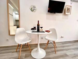 een witte tafel met twee witte stoelen en een fles wijn bij New-Romantic studio near the beach! in Paço de Arcos