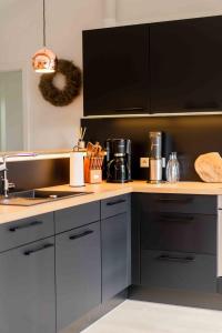 eine Küche mit schwarzen Schränken und einer Arbeitsplatte in der Unterkunft Studio EINS in Oersberg
