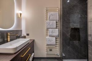 a bathroom with a sink and a shower with towels at Les Suites de l'Ile Barbe in Lyon