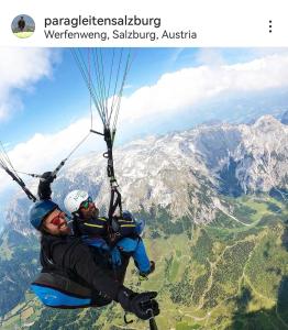 dos personas colgando de un paracaídas en las montañas en Jack's Apartment, en Werfenweng