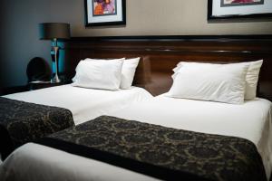 two beds in a hotel room with white sheets and pillows at Amérian Executive Córdoba Hotel in Córdoba