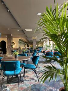 una cafetería con mesas, sillas y plantas en CONTI HOTEL VILNIUS, Conference Centre, Restaurant & Bar en Vilna