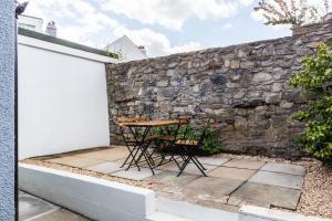 een tafel en stoelen op een patio naast een stenen muur bij Luxury House in the Heart of Mumbles Village in The Mumbles