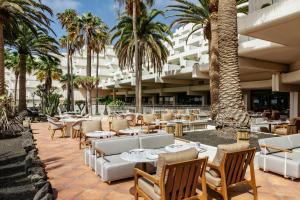 コスタ・テギセにあるParadisus by Meliá Salinas Lanzarote - All Inclusive - Adults Onlyのヤシの木が植わる屋外パティオ(テーブル、椅子付)