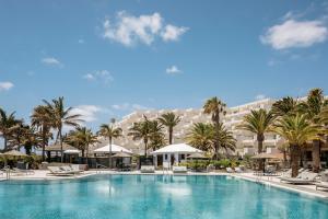 une grande piscine bordée de palmiers et un grand bâtiment dans l'établissement Paradisus by Meliá Salinas Lanzarote - All Inclusive - Adults Only, à Costa Teguise