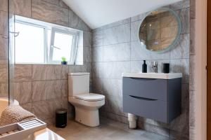 a bathroom with a toilet and a sink and a mirror at Luxury House in the Heart of Mumbles Village in The Mumbles