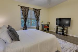 Un dormitorio con una cama blanca y un televisor de pantalla plana. en 4 Mi to Dtwn Pet-Friendly Abode in Tallahassee!, en Tallahassee