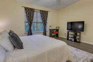 a bedroom with a white bed and a flat screen tv at Tallahassee Townhome with Patio Near FSU Campus! in Tallahassee