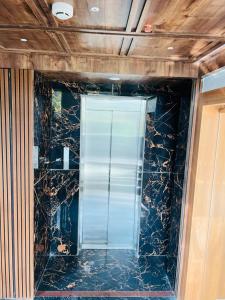 uma casa de banho com uma porta de vidro numa parede de mármore em HOTEL ROYAL VANILLA em Siliguri