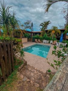 a swimming pool in a yard with tables and chairs at Pousada Aurora in Praia do Rosa