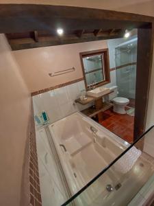 a bathroom with a tub and a toilet and a sink at Pousada Aurora in Praia do Rosa