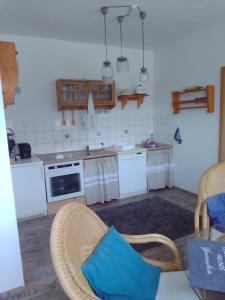 a kitchen with white appliances and a blue pillow on a chair at Ferienwohnung Zuschke in Klipphausen