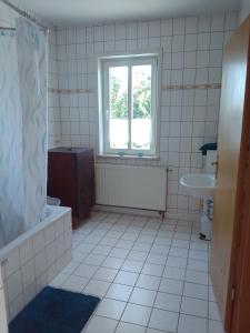 a bathroom with a tub and a sink and a window at Ferienwohnung Zuschke in Klipphausen