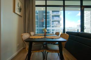 einen Tisch und Stühle im Wohnzimmer mit Fenster in der Unterkunft Contemporary 3BR Paradise on Franklin Street in Adelaide