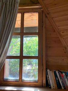 una ventana en una habitación con un estante de libros con libros en בקתת עץ בחורש במנות - דום גיאודזי - Wooden cabin in Manot, en Manot
