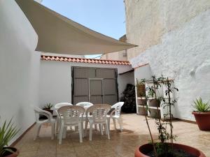 un patio con sillas blancas y una mesa y un edificio en Casa Josefa, en Pozo Alcón