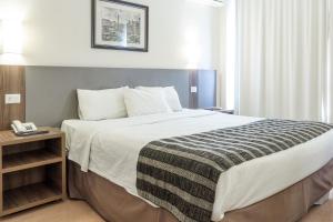 Un dormitorio con una cama grande y un teléfono en una mesa. en Lancaster Hotel by Castelo Itaipava en Curitiba