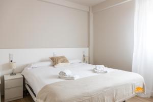 una camera da letto con un letto bianco e asciugamani di Malibu by Cadiz Time a Cadice