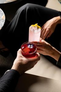 une personne tenant un verre dans un bol rouge dans l'établissement Academias Hotel, Autograph Collection, à Athènes