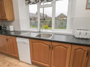 cocina con fregadero y ventana en South Cottage Howick, en Craster