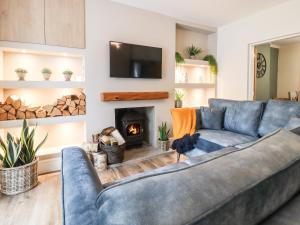 a living room with a blue couch and a fireplace at Cottage by the River in Burnley
