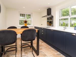 a kitchen with blue cabinets and a wooden table at Cottage by the River in Burnley