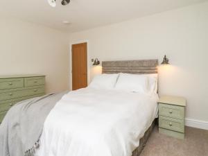 a bedroom with a large white bed and green cabinets at Cottage by the River in Burnley