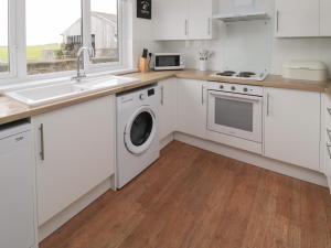 a kitchen with white cabinets and a sink and a dishwasher at Seaview Howick in Craster