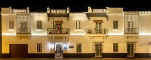 un gran edificio blanco con balcones por la noche en Albariza Hotel Boutique, en Sanlúcar de Barrameda