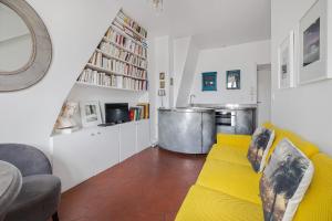 a living room with a yellow couch and a kitchen at Benjamine in Paris