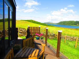 a wooden bench sitting on a porch with a view of the water at Balvicar Beag in Oban