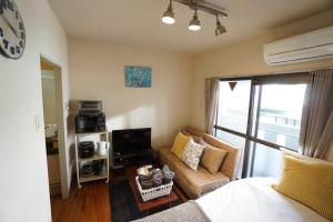 een kleine woonkamer met een bank en een televisie bij Apartment House Floor Assemble 402 in Osaka