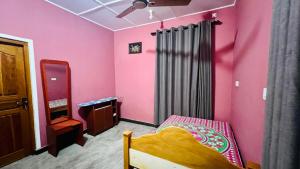 トリンコマリーにあるRamya’s Villaのピンクのベッドルーム(ベッド1台、鏡付)