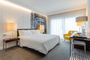 a bedroom with a large white bed and a desk at Olissippo Saldanha in Lisbon