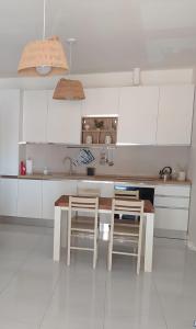 een keuken met witte kasten en een tafel en stoelen bij LECCE AL MARE in San Cataldo