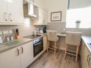 a kitchen with white cabinets and two chairs in it at The Moorings in Deganwy