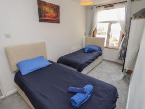 2 camas en una habitación con sábanas azules y ventana en Seaview Central en Southsea