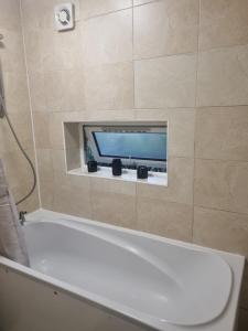 a bathroom with a bath tub with a tv on the wall at Manhattan Studio flat northbridge services in London