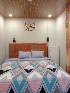 a bedroom with a bed with a colorful quilt at Vulkaan Homestay in Berastagi