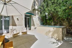 un patio con sombrilla, sillas y piscina en NOCNOC - Le Terrazzo - Petite piscine et jardin en ville en Montpellier